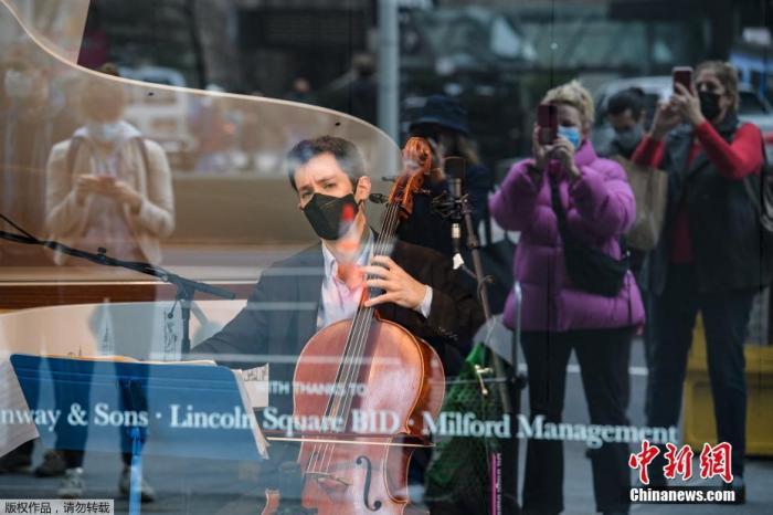 当地时间3月25日，美国纽约音乐人在空旷橱窗里演奏音乐，引路人围观拍照。据悉，100多名音乐人都参加了这一音乐会系列。