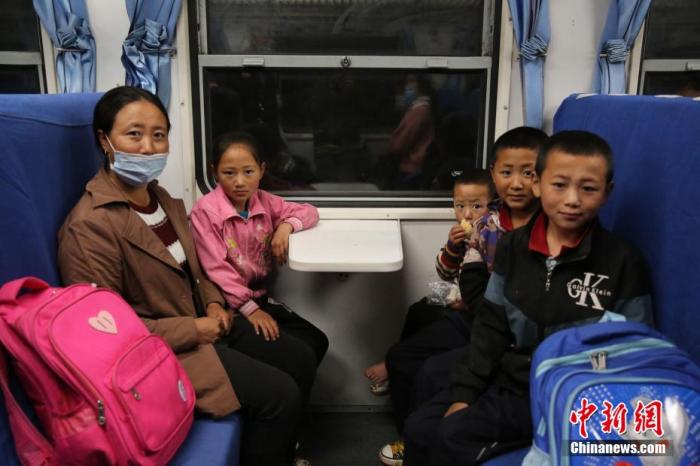 每到周日，这又成为学生娃们的“校车”，车厢内常见他们结伴上学，讨论家庭作业，分享彼此的小秘密……图为彝族妇女带着自己的四个孩子坐上5633次慢火车。 陶静 摄