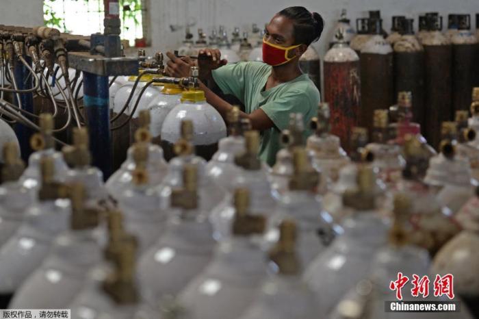 印度疫情蔓延导致多地医院出现供氧危机，许多医务人员、工作人员和普通民众都带着氧气瓶到氧气加气站。图为一名工人在钦奈郊区的一个设施中填充了医用氧气瓶。