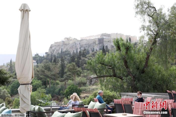 资料图：希腊雅典，人们在一家露天咖啡享用饮品。