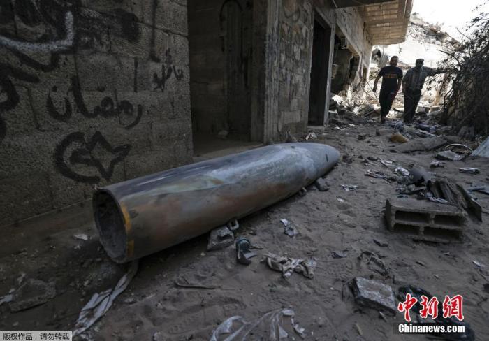 当地时间5月18日，巴以冲突持续，加沙地带一居民区出现一枚未引爆的炸弹。图为炸弹倒卧在一幢房屋门前。