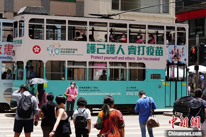 资料图：5月19日，一辆印有“护己护人 齐打疫苗”车身广告的电车驶过香港湾仔街头。 中新社记者 张炜 摄