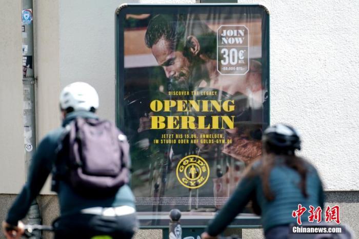 5月19日，德国全国范围内的“平均每十万人七日累计确诊数”已降至72.8。从当天起，柏林等多个州开始小幅实施“解封”，餐馆酒吧可重新经营户外业务，露天举行的文化活动和博物馆、泳池等设施亦获准重启。 图为当天下午，骑车的柏林市民经过一处写有“重启柏林”的健身房广告。 中新社记者 彭大伟 摄
