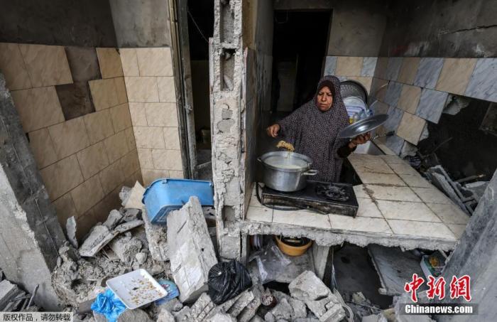 当地时间5月21日，加沙地带，一名妇女在破损的家中做饭。