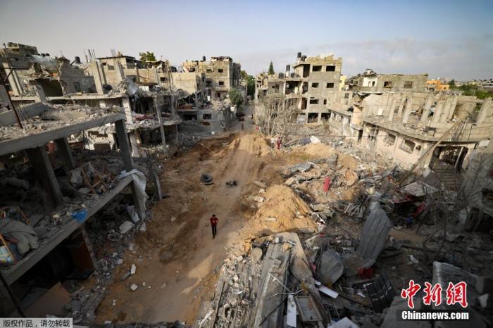 当地时间5月21日，加沙地带，一名男子在被炸毁的废墟中行走。