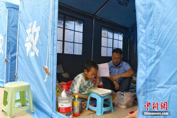 图为一名小男孩在避难点安置帐篷里做作业。　 中新社记者 刘冉阳 摄