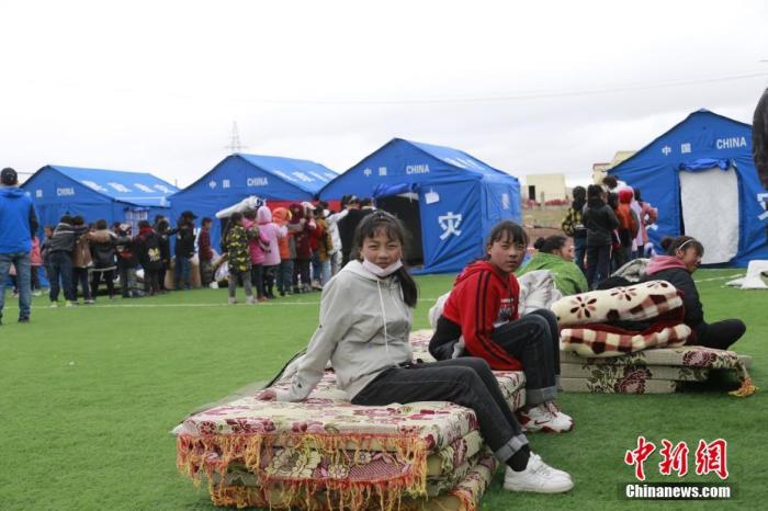 5月22日，在青海省果洛藏族自治州玛多县黄河乡藏文寄宿制学校安置点内，学生坐在床垫上等待入住救灾帐篷。 中新社记者 马铭言 摄