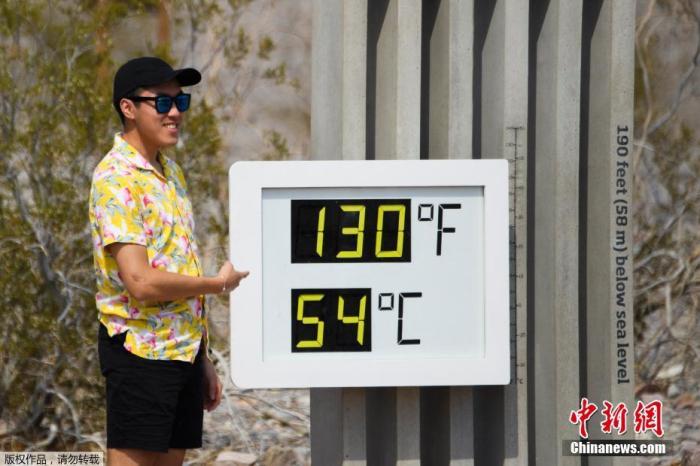 当地时间6月17日，美国加利福尼亚州死亡谷国家公园迎来54摄氏度的高温天气。图为游客与门口的温度显示器合影。