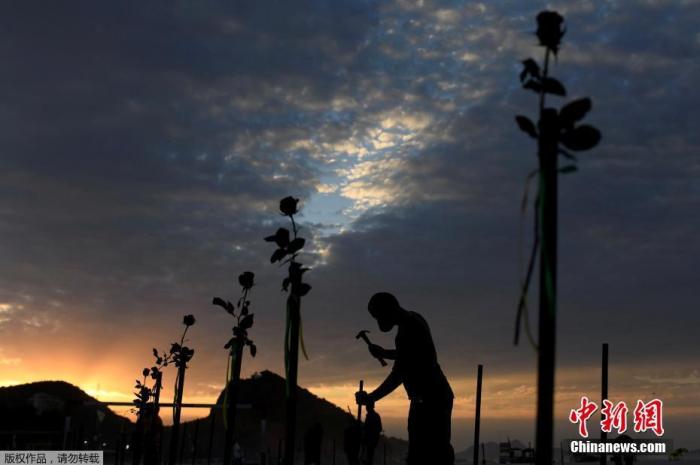 当地时间6月20日，巴西里约热内卢科帕卡巴纳海滩上摆放着玫瑰花，悼念巴西超50万的新冠逝者。图为民众在沙滩上“种玫瑰”。