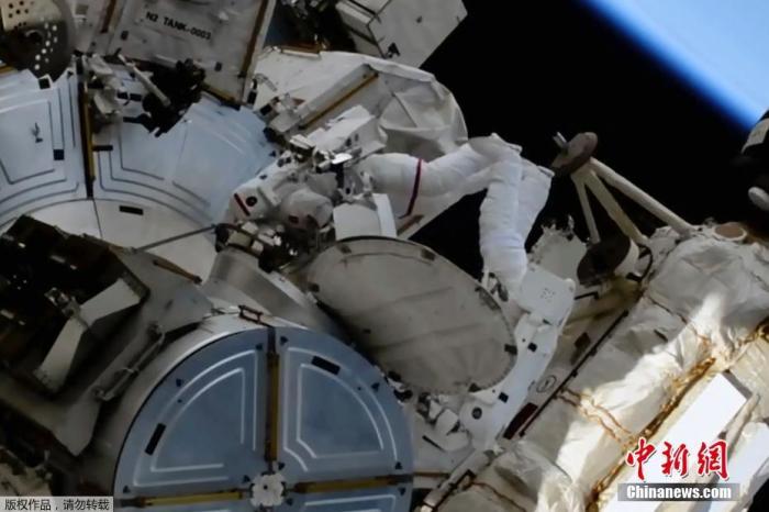 当地时间6月20日，美联社发布国际空间站宇航员执行太空行走任务的视频截图。图片显示国际空间站的两位宇航员进行太空行走并安装太阳能电池板。