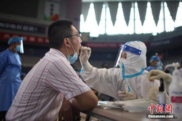 7月22日，江苏省南京市，设立在鼓楼区五台山体育馆的核酸检测点内，医务人员在为市民进行核酸检测取样。为进一步快速有效阻断新冠肺炎疫情扩散，江苏省南京市从7月21日开始对全市常住人口、外来人员开展全员核酸检测，目前正有序开展中。 /p中新社记者 泱波 摄