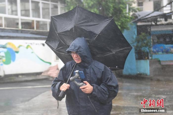 7月26日，浙江嘉兴，一名媒体记者的雨伞被吹翻。 /p中新社记者 王刚 摄
