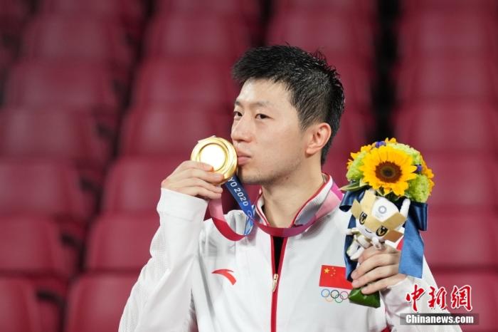 7月30日晚，东京奥运会乒乓球男单决赛迎来中国选手“内战”。最终马龙以4：2战胜樊振东，成功卫冕冠军。这是中国代表团在本届奥运会的第19金。图为马龙亲吻奥运金牌。/p中新社记者 韩海丹 摄