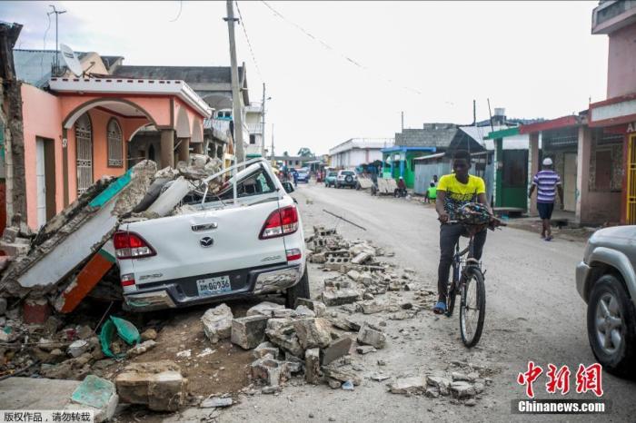 当地时间8月15日，海地Les Cayes，汽车被倒塌的建筑砸毁。据俄罗斯卫星网15日报道，根据海地民防部门的数据，海地强震已导致1297人遇难。据称，至少有5700人在地震中受伤。