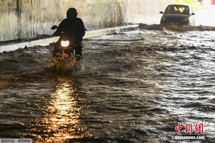 当地时间9月11日，印度新德里，一场暴雨过后路面积水严重，民众骑摩托车进入充满积水的隧道。