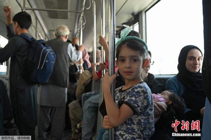 资料图：阿富汗喀布尔机场，包括妇女儿童在内的乘客乘坐摆渡车。