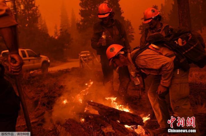 当地时间9月22日，美国加州红杉国家公园山火持续，浓烟遮天蔽日。图为消防员等待水管时用嘴喷水灭火。