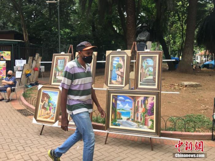 当地时间10月3日，巴西圣保罗，一名游客从一个街头画摊前走过。中新社记者 莫成雄 摄
