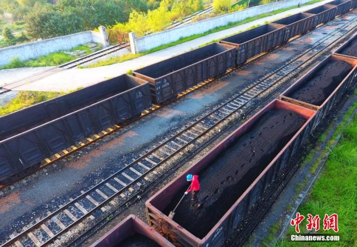 资料图：在江西省九江市濂溪区的江西省煤炭储备中心，工人们正在平整货物列车上的电煤。 胡国林 摄
