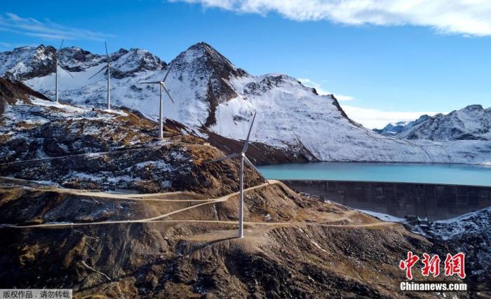 当地时间10月25日，瑞士格里斯湖前的风车。在最新的一项研究中，瑞士科学家确定了自 1850年代以来在瑞士阿尔卑斯山形成的1200多个冰川湖。随着气温持续上升，冰川融化成湖泊，阿尔卑斯山区正面临越来越大的冰川湖溃堤风险。