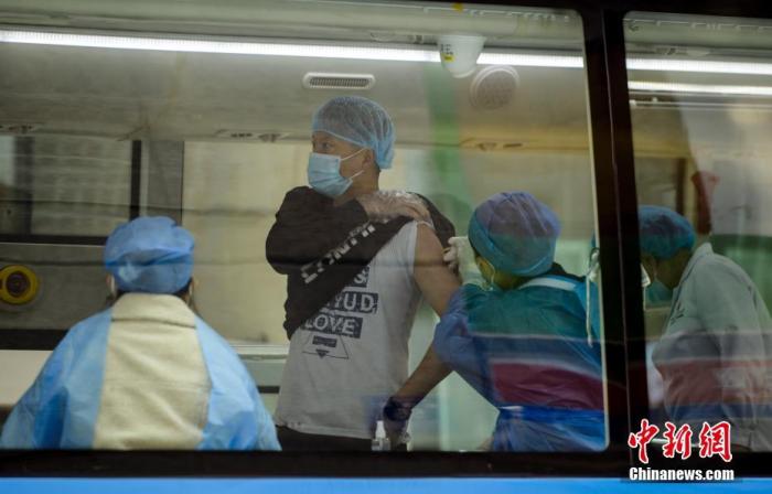 11月1日，新疆乌鲁木齐市天山区大小西门商圈，市民在移动疫苗接种车上接种新冠疫苗。据介绍，该市首台移动疫苗接种车已正式启用，为民众提供新冠疫苗接种服务。 中新社记者 刘新 摄