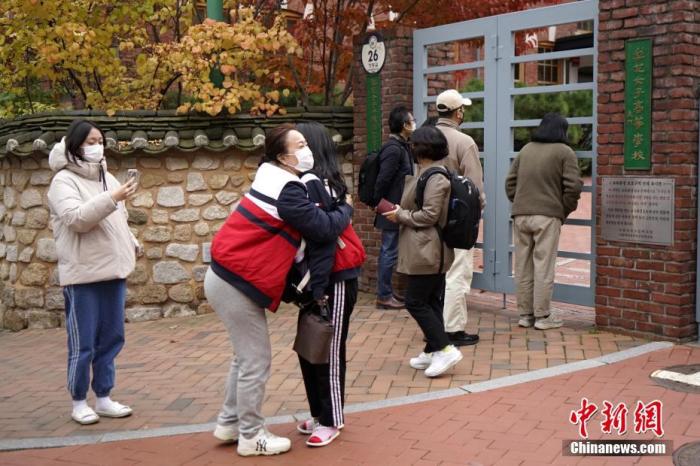 资料图：当地时间2021年11月18日上午，韩国2022学年大学修学能力考试（高考）在韩国全国86个考区如期开考。韩媒报道称，今年有509821人报名参加考试，同比增加3.3%。图为首尔梨花女子高中门口，送考家长拥抱考生。 /p中新社记者 刘旭 摄