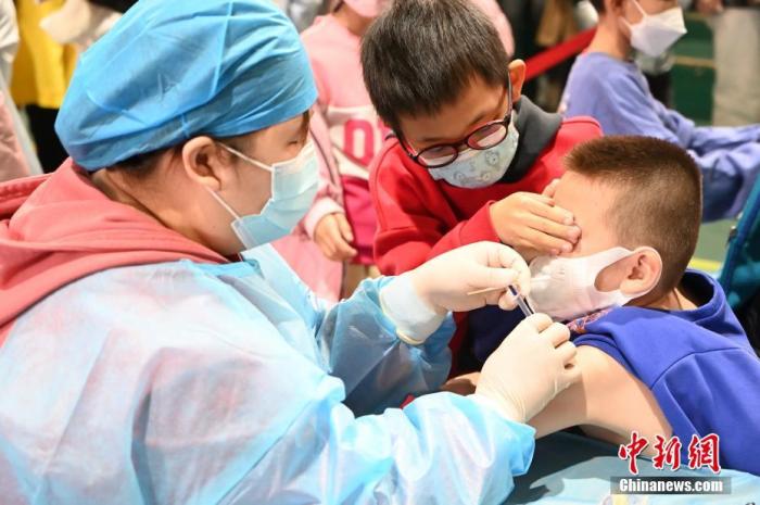 11月20日，一名儿童接种新冠病毒疫苗，一旁的小伙伴为其遮住眼睛。近日，内蒙古呼和浩特市启动了3至11岁儿童新冠病毒疫苗接种工作。 中新社记者 刘文华 摄