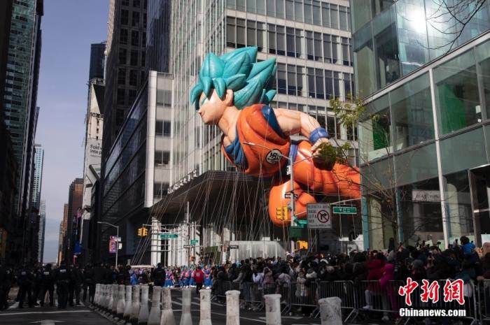 當地時間11月25日，第95屆梅西百貨感恩節遊行在紐約曼哈頓舉行。去年遊行受新冠疫情影響參與人數縮減了88%，今年遊行已經恢復疫情前的規模。遊行由15個巨型氣球、28輛花車以及行進表演組成，吸引眾多民眾沿街觀看。圖為巨型氣球“悟空”穿過十字路口。 <a target='_blank' href='/'><p  align=