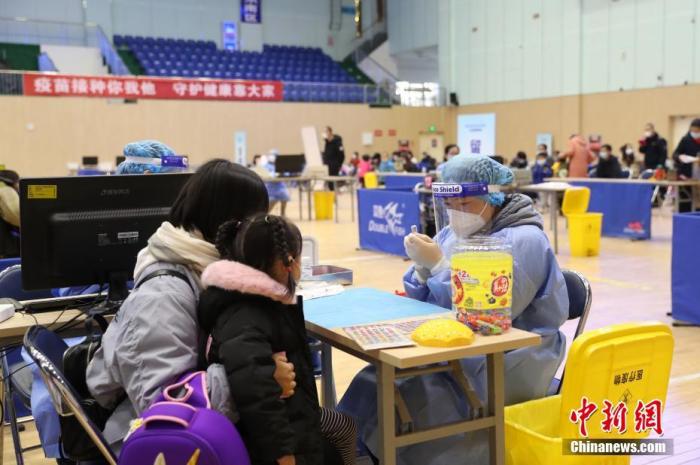 资料图：家长带着孩子接种疫苗。中新社记者 于晶 摄