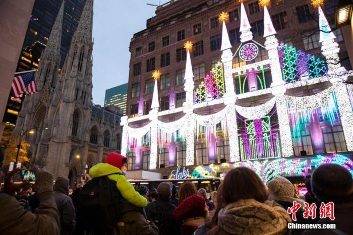 当地时间12月8日，随着圣诞节的临近，越来越多的圣诞装饰亮相美国纽约街头，吸引路人驻足欣赏。图为人们驻足观看第五大道百货公司圣诞灯光秀。 中新社记者 廖攀 摄