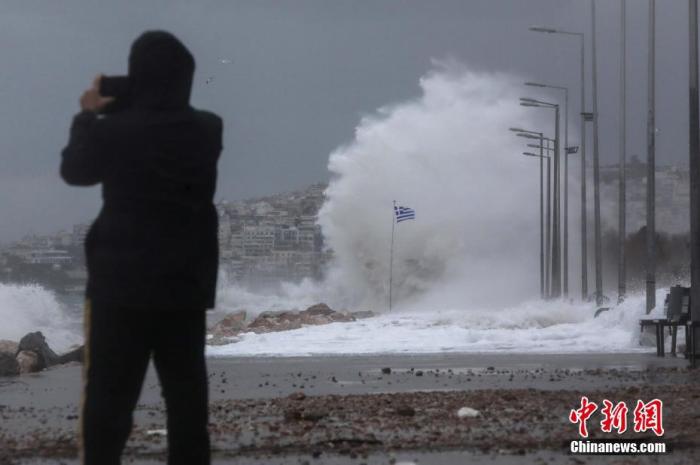 当地时间2021年12月11日，希腊古法利罗，暴风雨中，民众观看海浪冲击码头并拍照。 图片来源：ICphoto