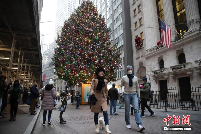 当地时间2021年12月24日，人们经过美国纽约华尔街上布置的一棵圣诞树。在新一轮新冠肺炎疫情中，当地迎来圣诞节平安夜。 中新社记者 廖攀 摄