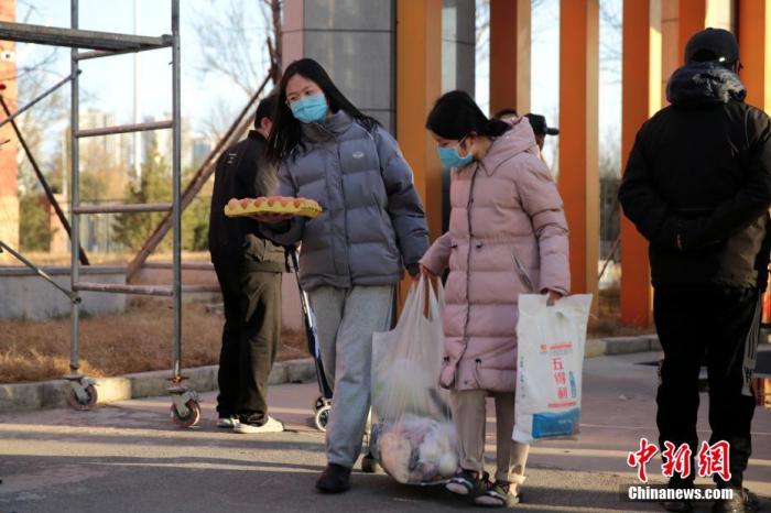 图为居民领取蔬菜等物资。 张远 摄 图为居民领取蔬菜等物资。 张远 摄