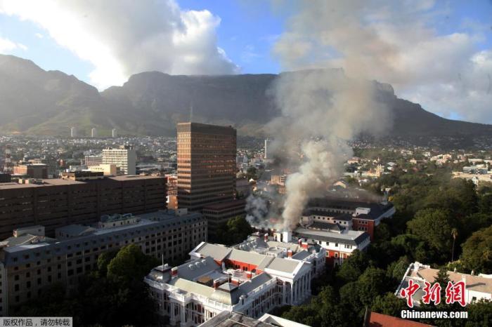当地时间2022年1月2日，南非首都开普敦的议会大厦起火，现场浓烟滚滚。图为全景图展示火灾现场。