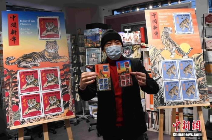 当地时间1月22日，法国邮政在巴黎举行虎年生肖邮票发行仪式，迎接中国新春佳节。图为生肖邮票设计师、法籍华裔画家陈江洪在仪式现场向大家展示邮票。 中新社记者 李洋 摄