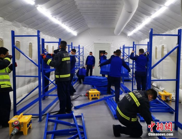 资料图：杭州搭建气膜方舱移动实验室助力抗疫。图为消防队员和工作人员在气膜方舱移动实验室内搭建支架。 杭州消防供图