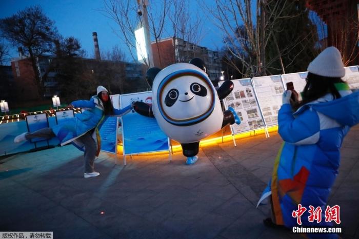 2月4日，在北京2022年冬奥会开幕式前，一名志愿者在奥运文化中心与北京2022年冬奥会吉祥物“冰墩墩”合影留念。