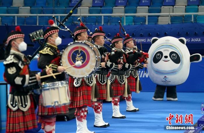 2月18日，2022北京冬奧會男子冰壺銅牌賽，冰墩墩賽前拿起指揮棒指揮蘇格蘭風笛樂隊進行演出。圖片來源：視覺中國
