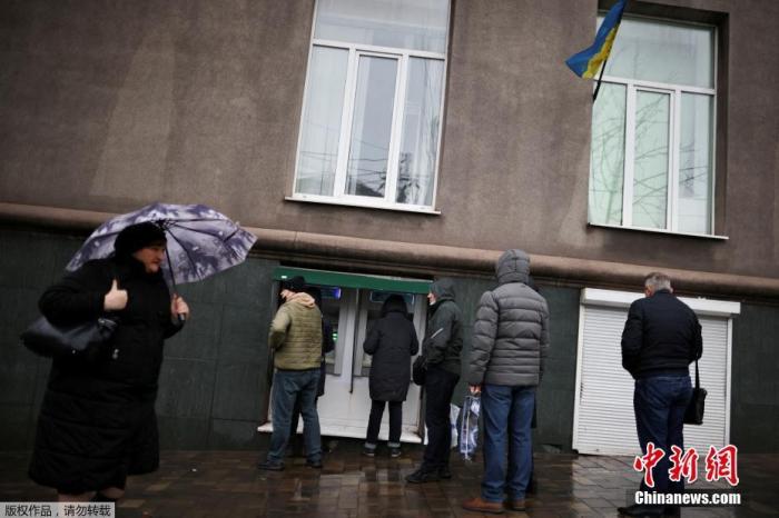 当地时间2月24日，乌克兰局势急剧恶化，多地民众在自动提款机前排长队提取现金。图为马里乌波尔市民在街头排队取钱。