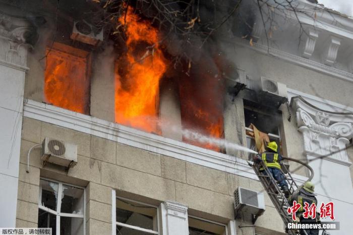 资料图：当地时间3月2日，乌克兰哈尔科夫的警察局大楼附近遭到炮火袭击，警察局大楼楼顶燃起大火。图为消防人员正在灭火。