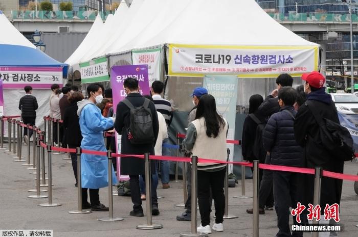 当地时间3月17日，一名医务人员在韩国首尔的一个临时检测点指导等待新冠病毒检测的人。