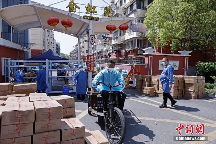 图为工作人员在上海金虹苑门口将生活物资运抵小区内，并发放至居民家中。 殷立勤 摄