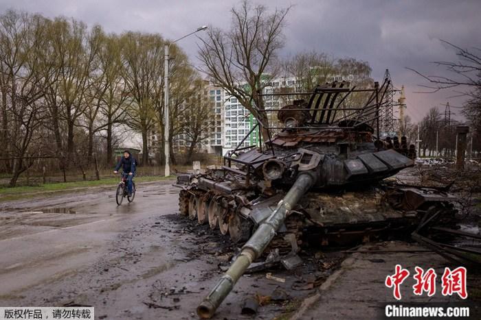 資料圖：烏克蘭切爾尼夫，一名男子騎著自行車在一輛被毀的坦克旁騎車。
