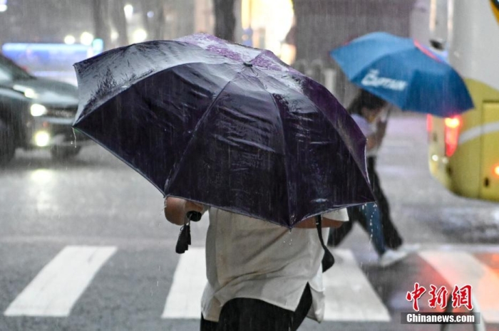 资料图：市民在雨中出行。 中新社记者 陈骥旻 摄