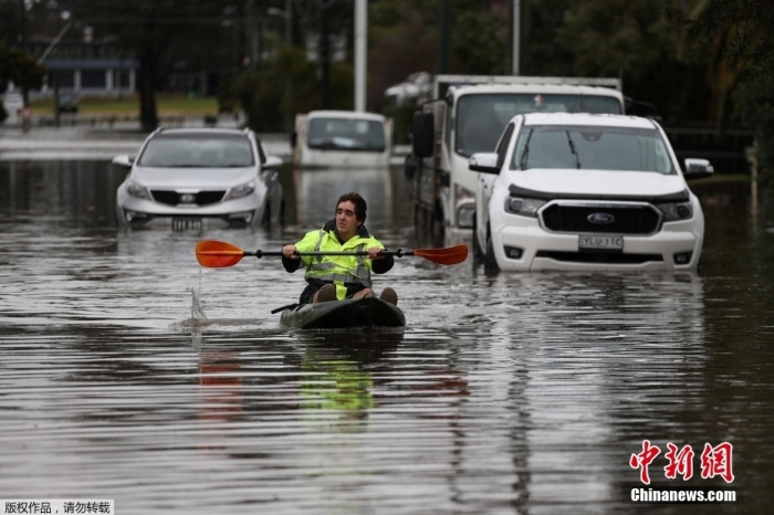 近日，澳大利亚悉尼西部和西南部部分地区因持续性降雨，建筑和道路被暴雨引发的洪水淹没，约5万居民紧急撤离。图为澳大利亚悉尼南温莎郊区，一位居民在暴雨后划皮艇穿过被淹没的居民区。
