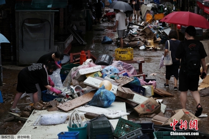 当地时间2022年8月9日，韩国首尔一家市场内员工们正在清理被暴雨毁坏的物品。