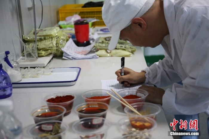 8月14日，广西柳州市螺蛳粉生产企业的一名试辣师对一批新生产的袋装螺蛳粉中的辣油包进行测试后，在测评表格中填写各种感官体验和辣度。 中新社记者 蒙鸣明 摄