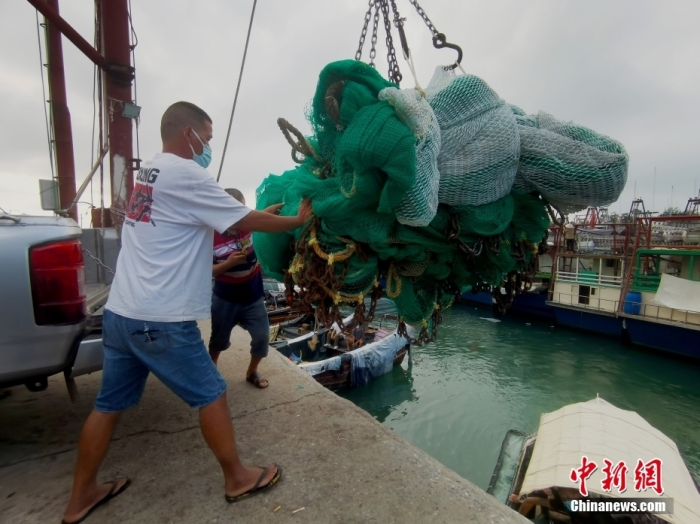 8月16日，广西北海市侨港镇电建渔港，渔民在吊运渔具上船。 中新社记者 翟李强 摄
