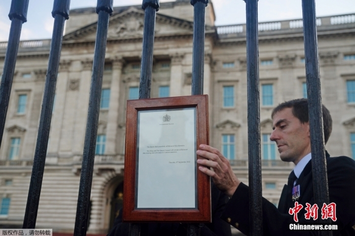 图为王室工作人员将英国女王伊丽莎白二世去世的公告挂在白金汉宫大门上。