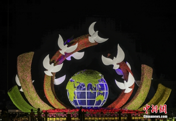 资料图：2022年9月26日晚，北京长安街沿线国庆主题花坛亮灯，市民在参观军事博物馆前广场布置的“命运共同体”花坛。 中新社记者 易海菲 摄